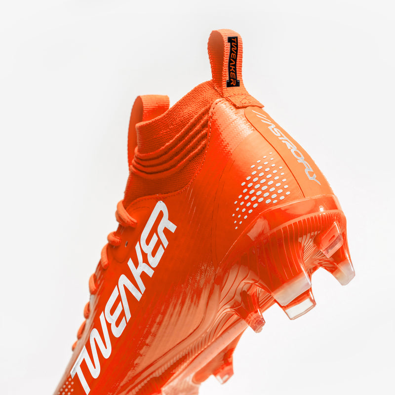 A pair of bright orange football cleats with white 'BATTLE', displayed on a clean white background.