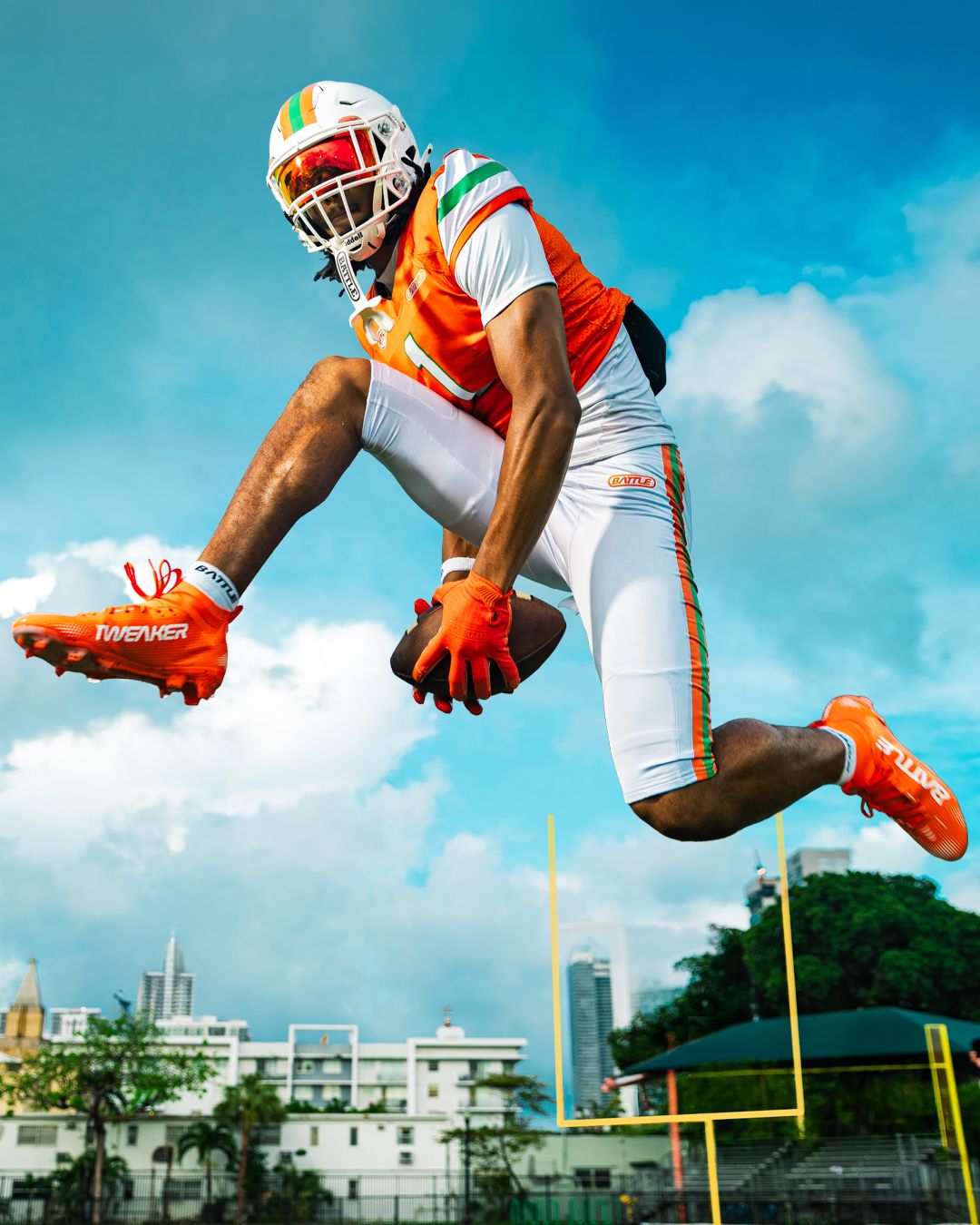 Brysen Wright airborne with the football wearing the neon orange AstroFly BFYE cleats
